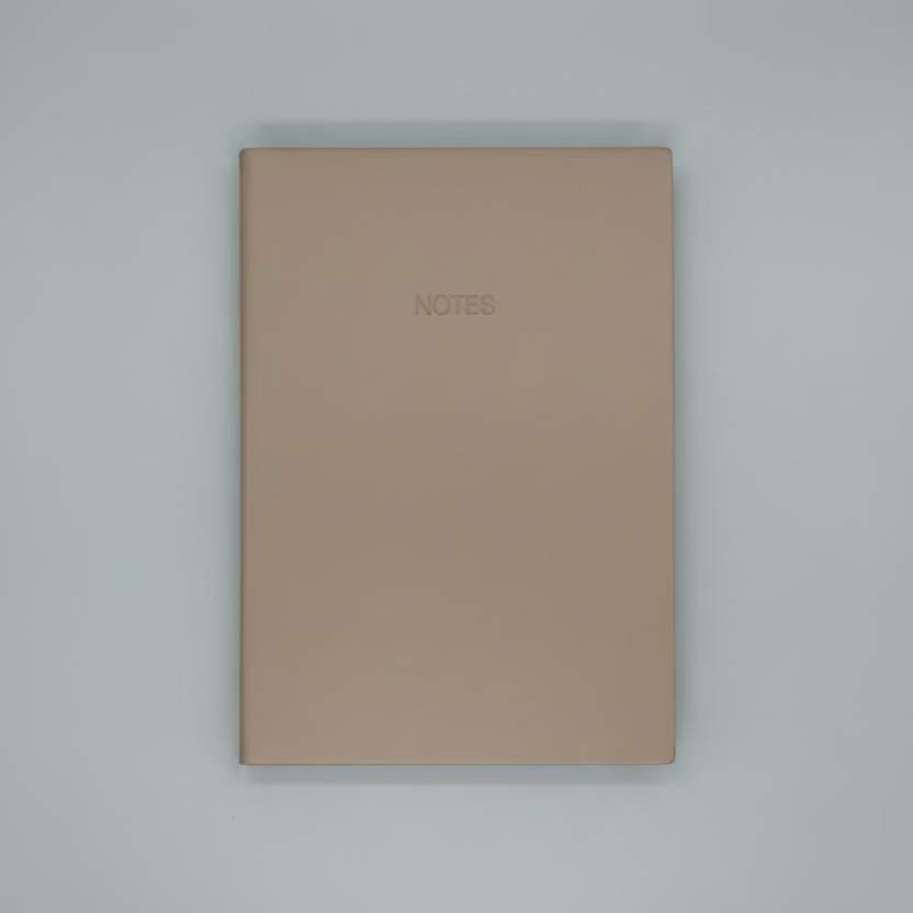 Beige notebook with 'NOTES' on a white surface with geometric black and white pattern